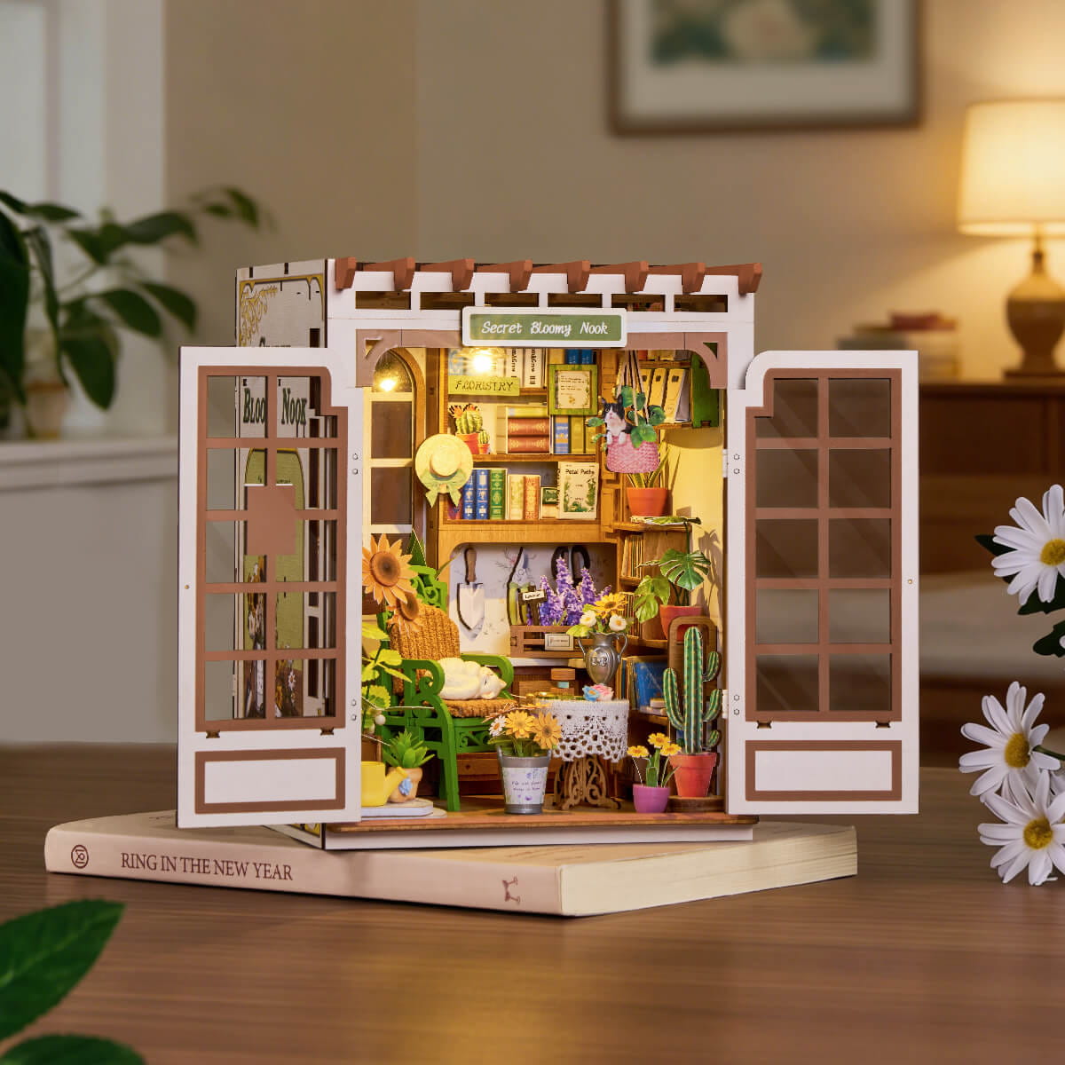 Wooden model of a store with various items on a wooden base, surrounded by plants and decor.