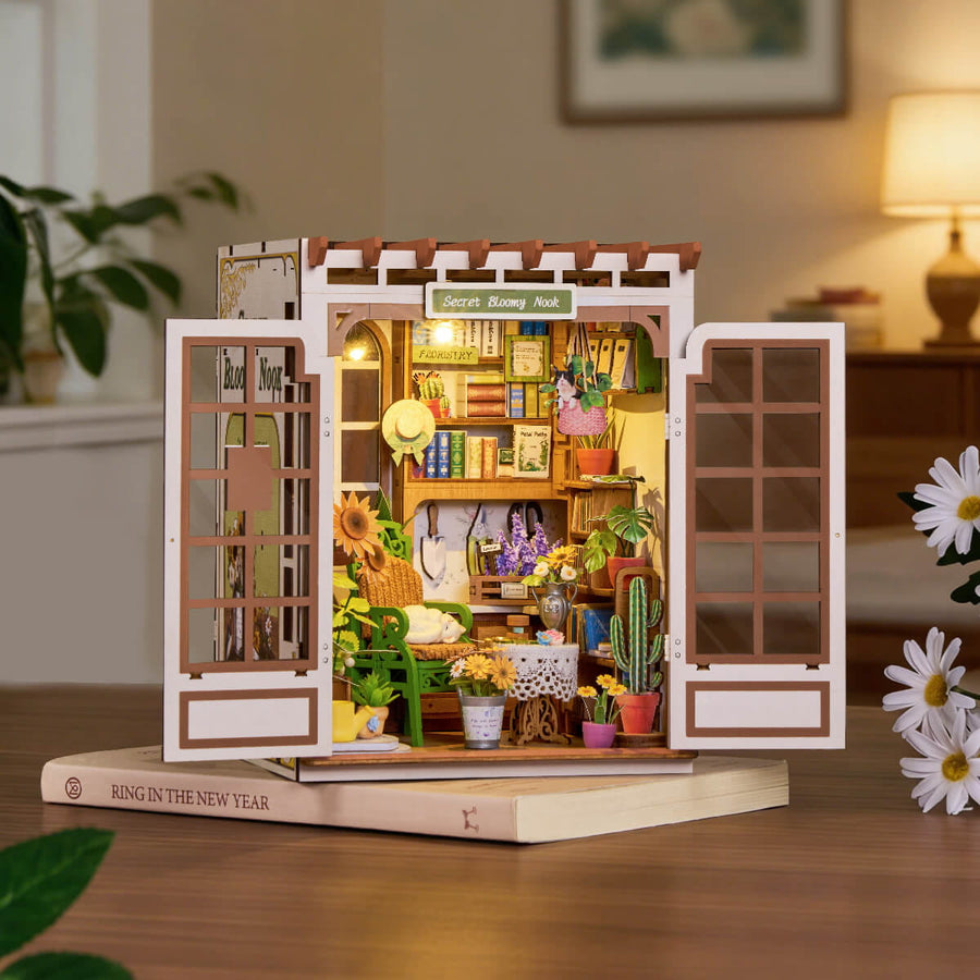 Wooden model of a store with various items on a wooden base, surrounded by plants and decor.