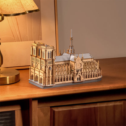 Wooden model of a cathedral on a wooden surface with a lamp in the background