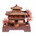 Wooden model of a traditional Japanese temple with cherry blossom trees on a white background