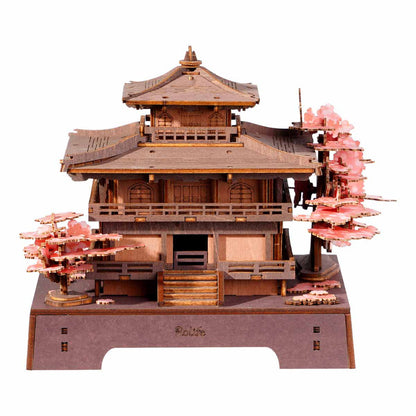Wooden model of a traditional Japanese temple with cherry blossom trees on a white background