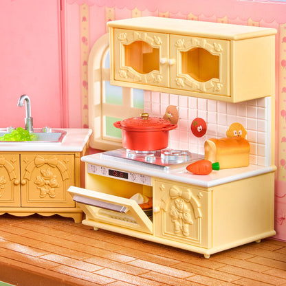 A miniature dollhouse kitchen set featuring a cream-colored play kitchen with decorative cabinet doors, a red toy pot, a sink, and toy food accessories, set against a pink dollhouse wall and wood-look floor.