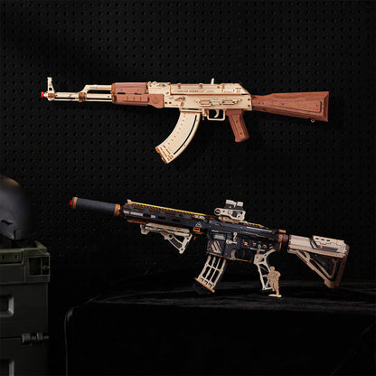 Two miniature replica-style rifle models displayed against a black pegboard background, with one mounted on the wall and one placed on a black surface below. A helmet and storage case are partially visible at the left edge.