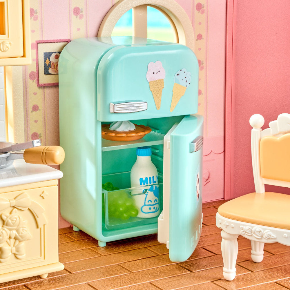 A mint green toy refrigerator with ice cream cone decals, shown open with miniature food items inside, set in a dollhouse-style kitchen with pink walls and a yellow chair.