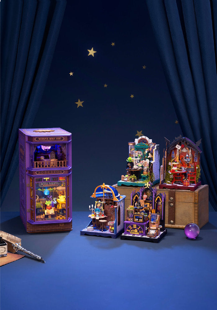 A set of miniature wizard-themed building block sets arranged on a blue surface against a dark blue curtain backdrop with gold stars. The collection includes a tall purple shop building, a small arched shop set, a multi-level magical room, and a purple crystal ball.