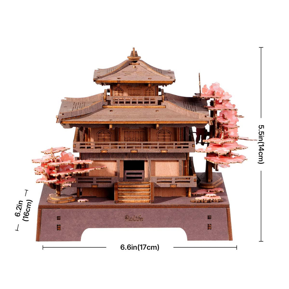 Wooden model of a Japanese temple with cherry blossom trees and measurements on a white background