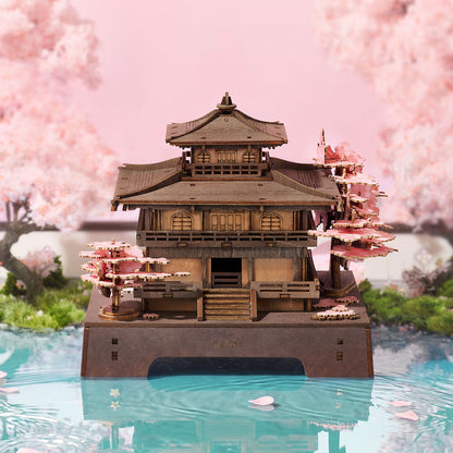 Model of a traditional Japanese temple with cherry blossom trees in the background