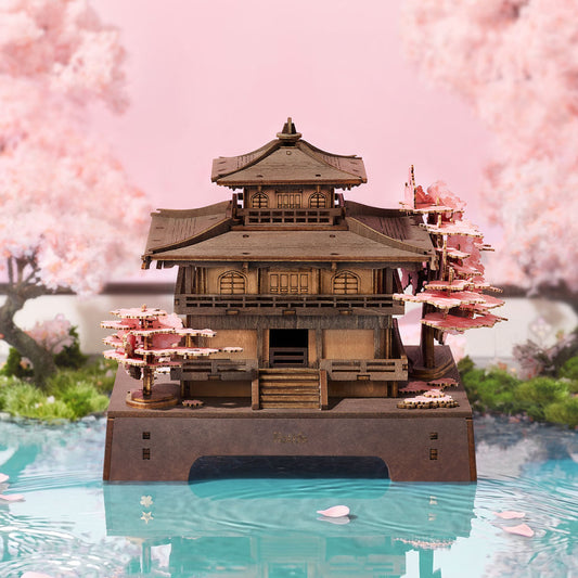 Model of a traditional Japanese temple with cherry blossom trees in the background