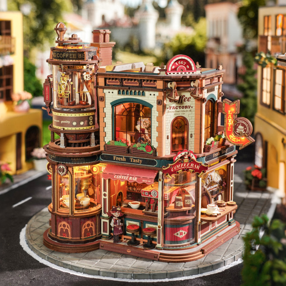 Detailed model of a coffee factory with lit signs and furniture, set against a blurred street background.