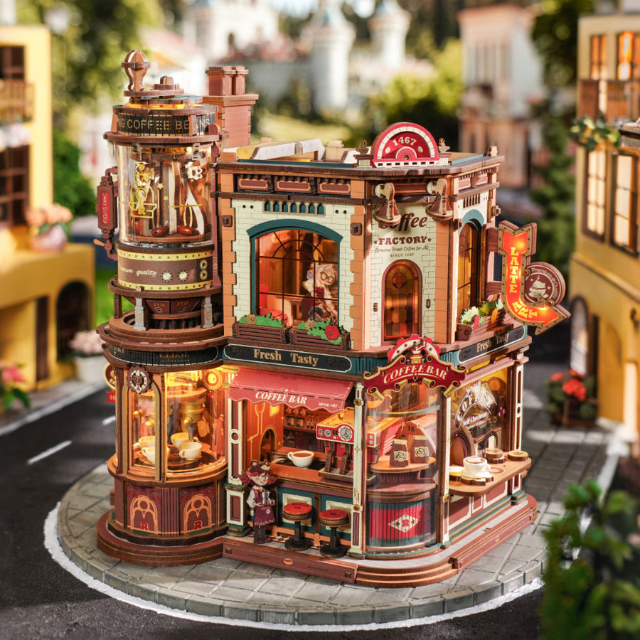 Detailed model of a coffee factory with lit signs and furniture, set against a blurred street background.