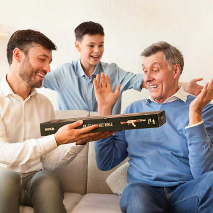 Two men and a boy sitting on a couch, with one man holding a box labeled 'Bolt Action Rifle'.