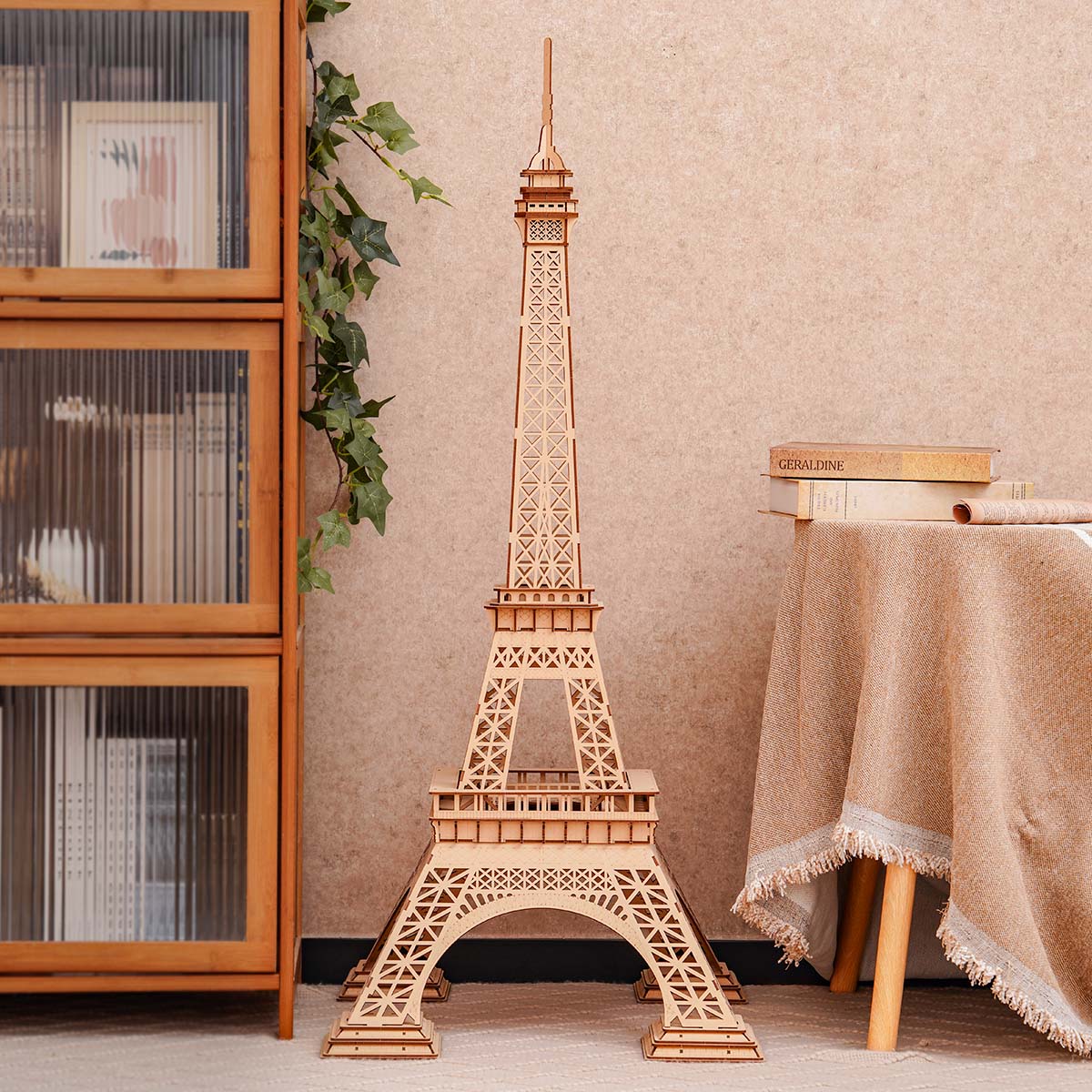 Wooden model of the Eiffel Tower in a room with a bookshelf and table.