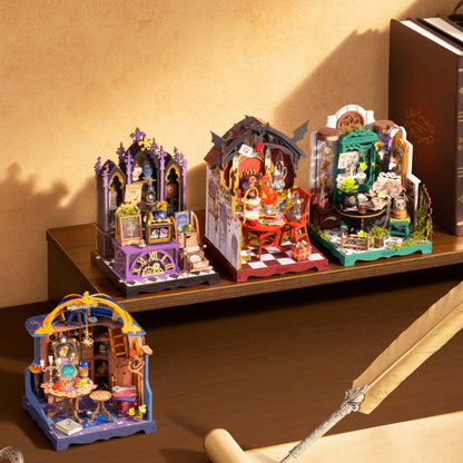 Four miniature gothic-style dollhouse dioramas displayed on a wooden shelf and table, featuring purple, red, green, and blue structures with tiny furniture and decorative details.