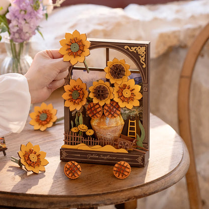 Decorative sunflower-themed gift box with a hand holding a sunflower, placed on a wooden surface.