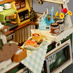 Toy coffee shop set with miniature coffee machine, cups, and flowers.