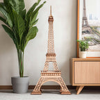 Wooden model of the Eiffel Tower in a room with a plant and framed picture.