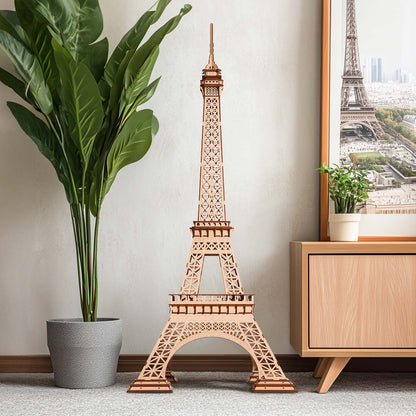 Wooden model of the Eiffel Tower in a room with a plant and framed picture.