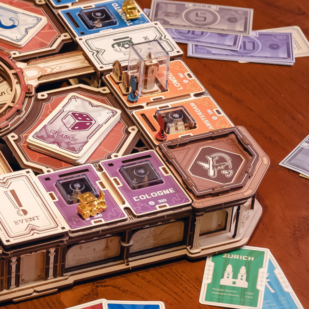 A close-up of a wooden building-block style board game set arranged on a wooden table, with cards, tokens, and small components visible. No person or animal is present, but the real tabletop environment is visible, so this fits Lifestyle rather than Product/Packaging.