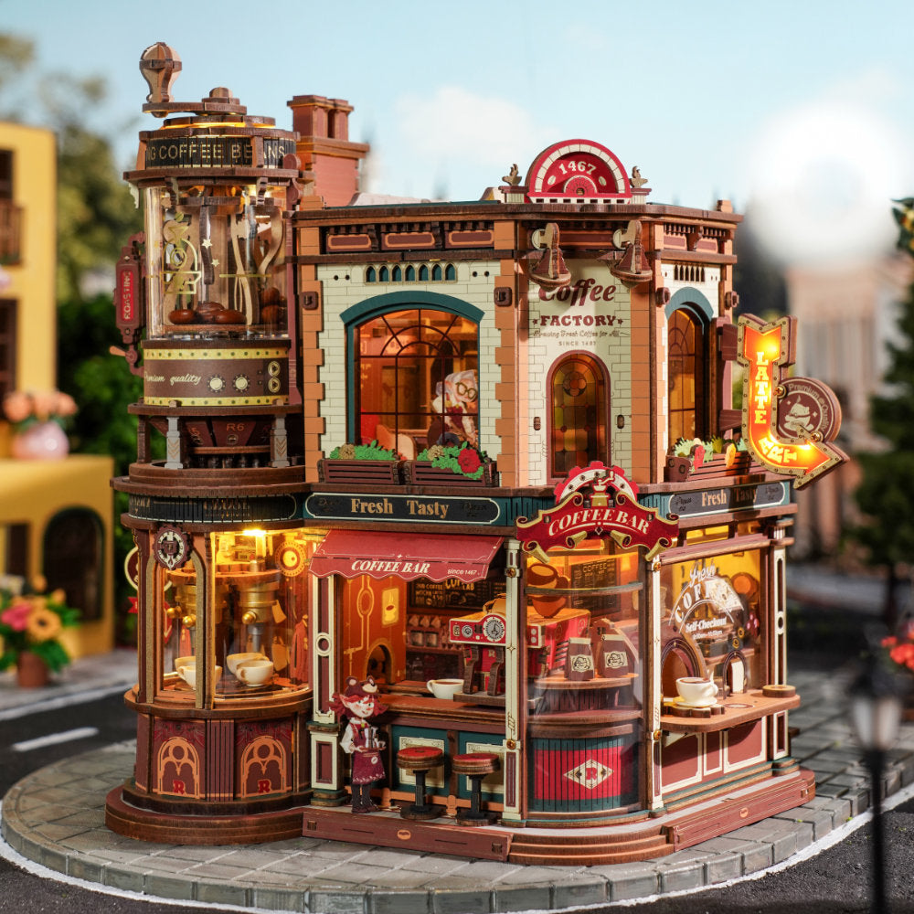 Detailed model of a coffee shop with illuminated signs and interior lights, set against a blurred street background.