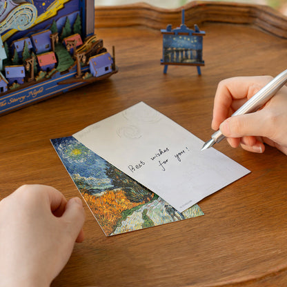 Person writing a card with a Van Gogh painting design on a wooden table.