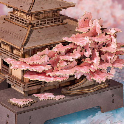 Wooden model of a traditional building with cherry blossom trees in front