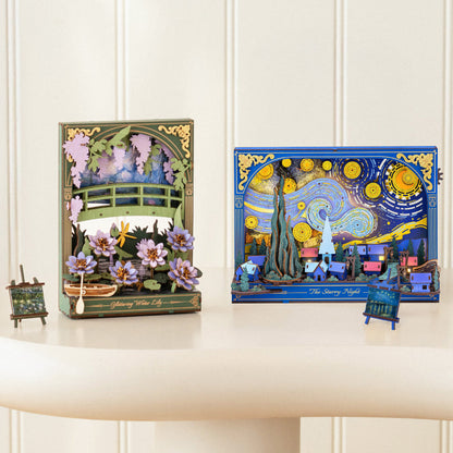 Two decorative 3D pop-up art boxes displayed on a cream-colored table against a white paneled wall. The left box features Van Gogh's 'Galaxy Flower City' with green and purple poppy fields and a bridge.