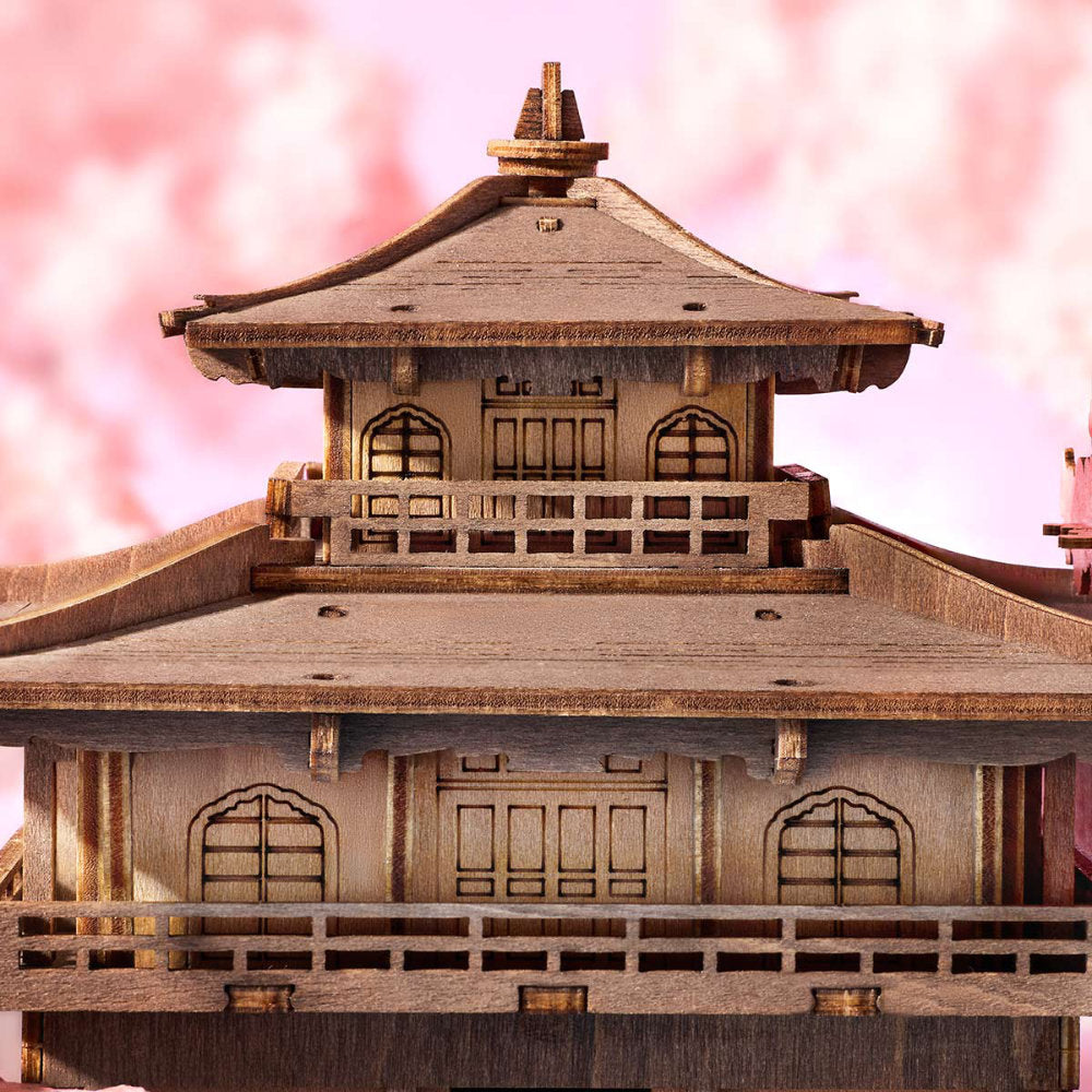Wooden model of a traditional Japanese building with cherry blossoms in the background