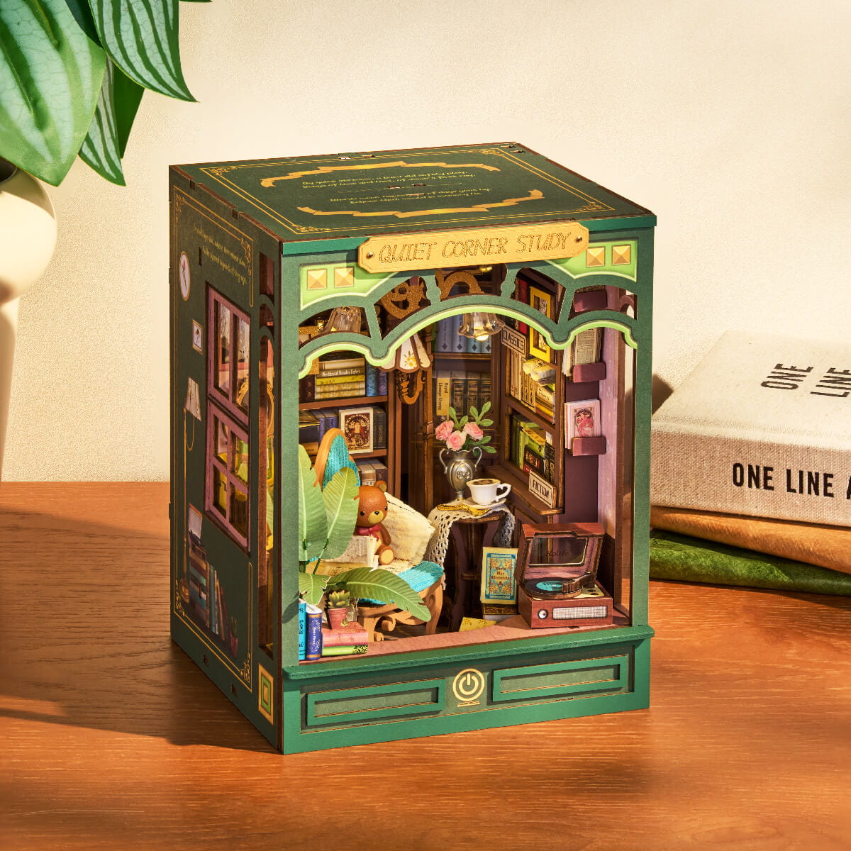 Detailed model of a cozy corner study inside a green box on a wooden surface.