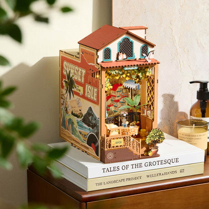 Miniature house model on top of books with a candle and plant in the background