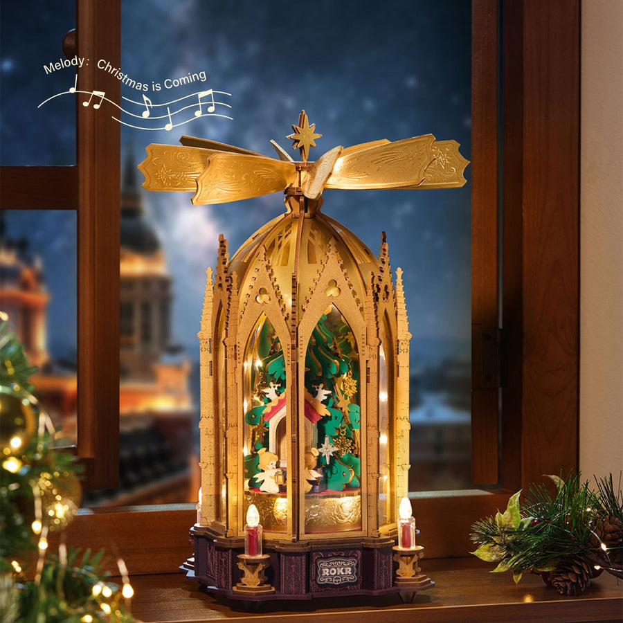 Wooden-Town Angel's Christmas Pyramid 3D wooden puzzle music box – lit pyramid on a windowsill at night with melody notes for Christmas Is Coming