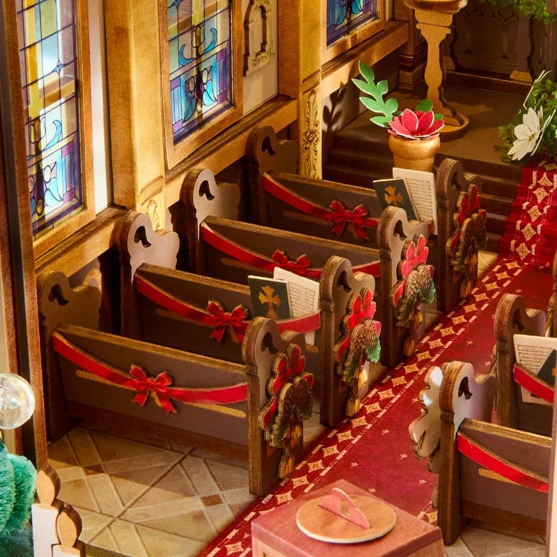 Wooden-Town Caroling Cathedral 3D wooden book nook kit – close-up of pews with red ribbon bows and hymn books beside stained-glass windows