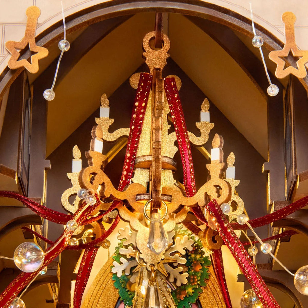 Wooden-Town Caroling Cathedral 3D wooden book nook kit – close-up of the gold chandelier with candles, red ribbons and clear beads