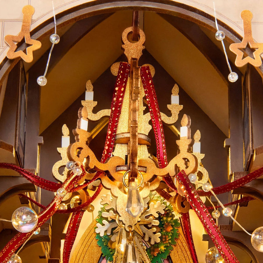 Wooden-Town Caroling Cathedral 3D wooden book nook kit – close-up of the gold chandelier with candles, red ribbons and clear beads