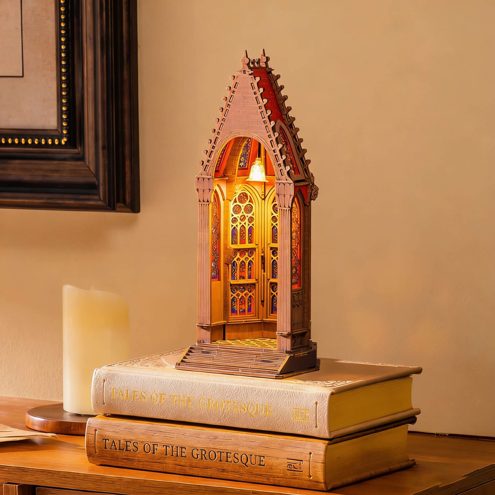 Decorative wooden lantern with stained glass design on top of books, candle in the background