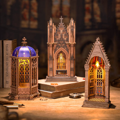 Three gothic-style model buildings with intricate designs on a wooden surface.