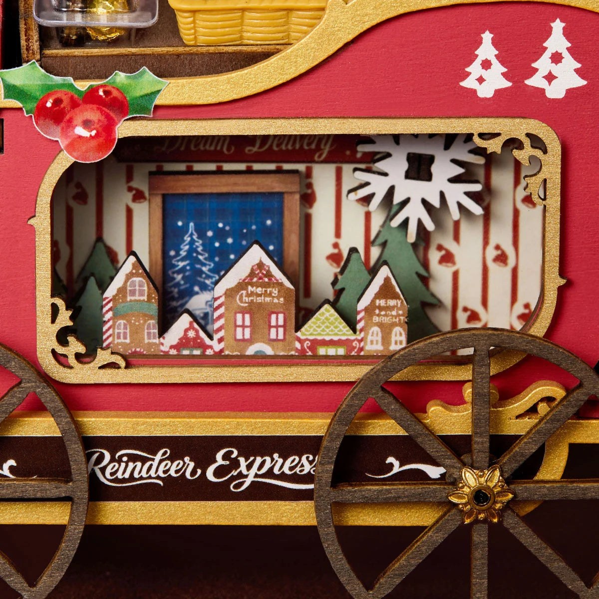 Wooden-Town Reindeer Express DIY miniature kit – close-up of the sleigh side panel with gold trim, holly and a window showing a gingerbread village
